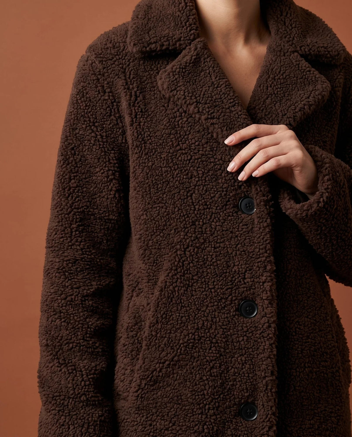 Close-up of coffee teddy fleece coat showing textured fabric and button fastening