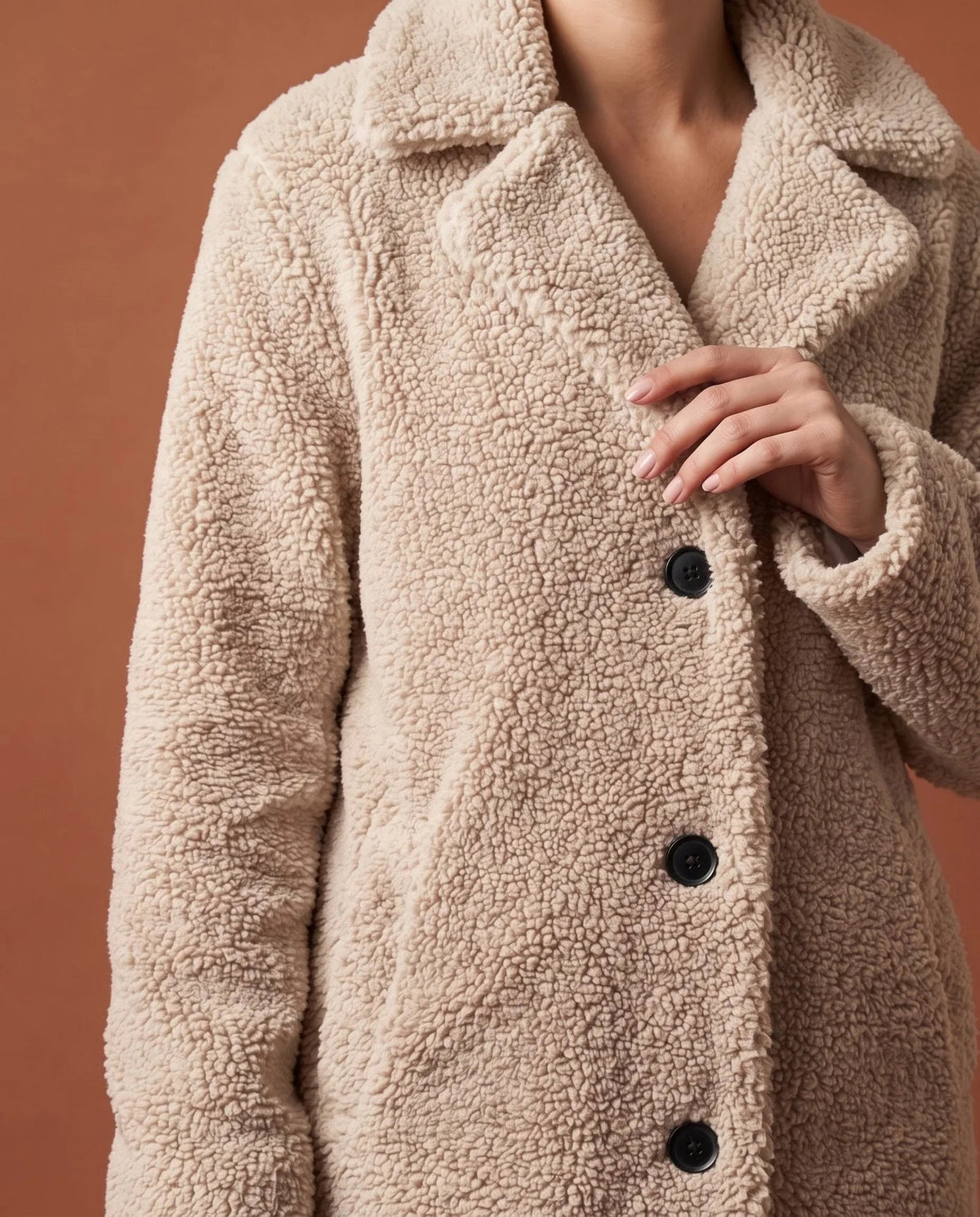 Close-up of white teddy fleece coat showing textured fabric and button fastening