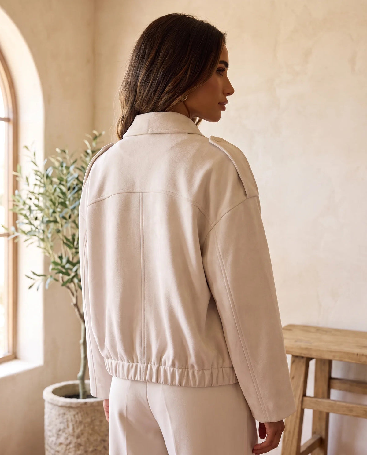 Back view of beige faux suede jacket showing dropped shoulders, seam detail and gathered hem