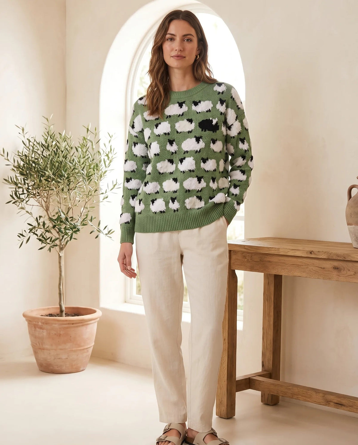 Women's green crew neck sweater with textured white sheep and a black sheep on the chest, front view