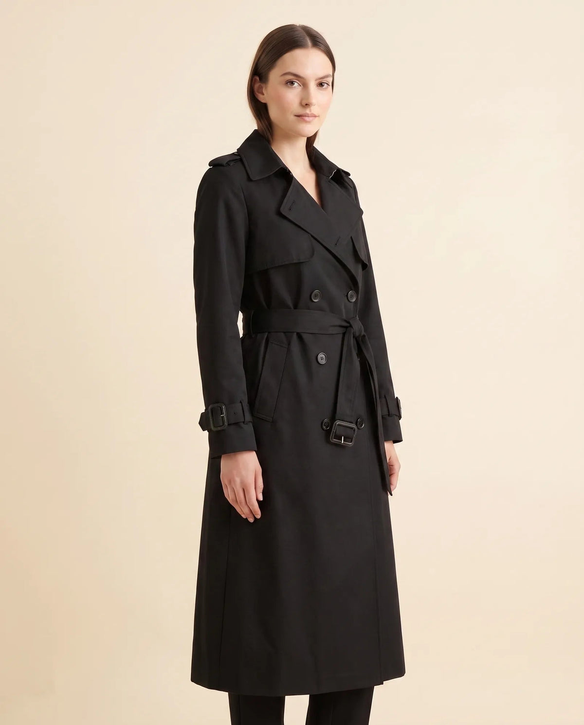 Angled view of black belted trench coat showing long sleeves and side pocket
