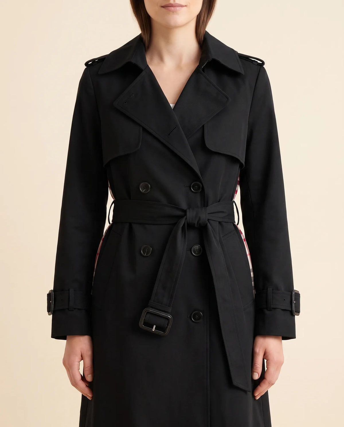 Close-up of black trench coat showing notched lapels, double-breasted buttons and waist belt