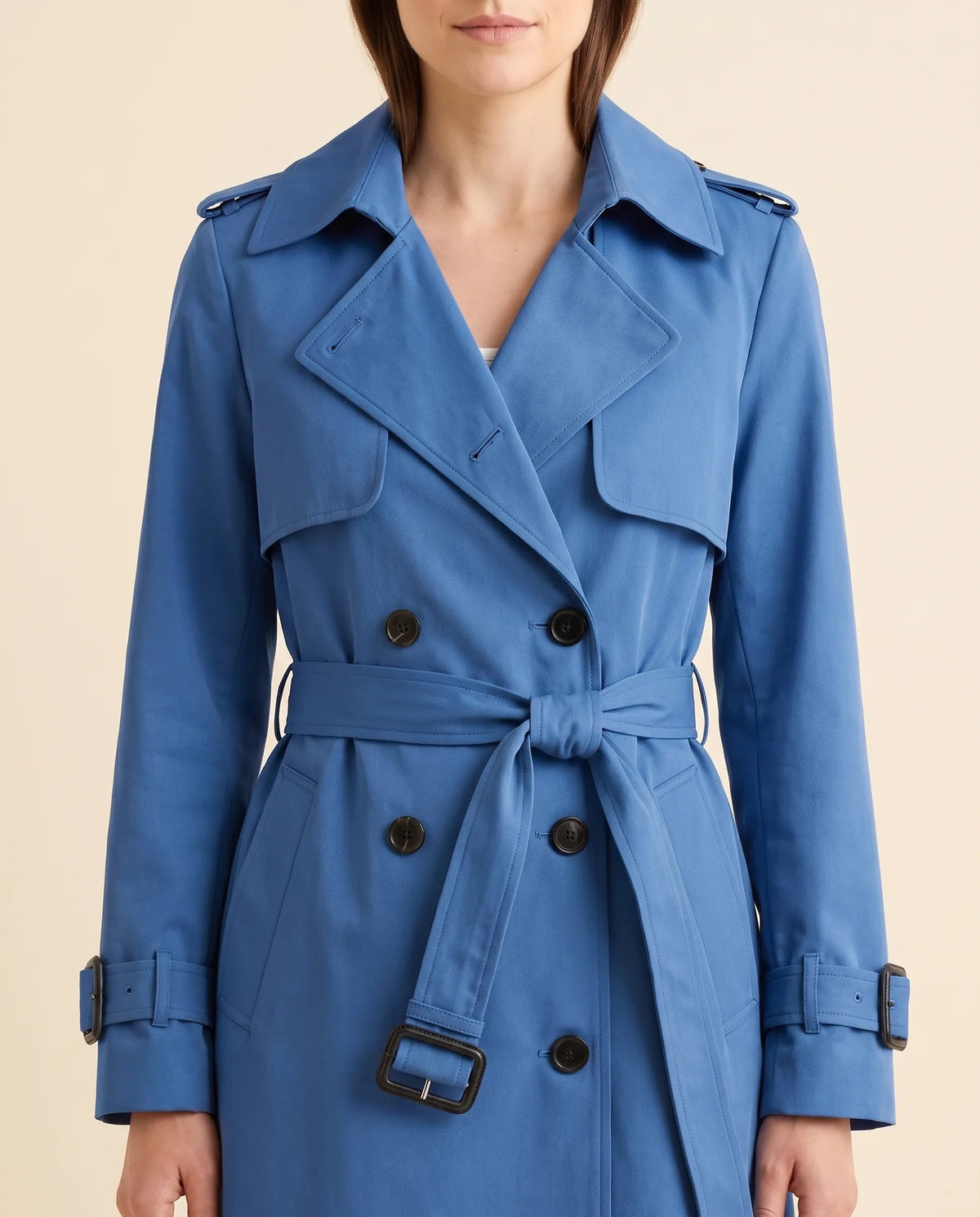Close-up of blue trench coat showing notched lapels, double-breasted buttons and waist belt