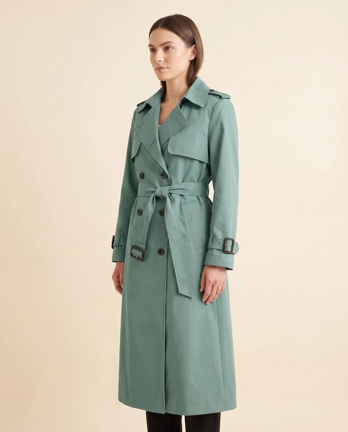 Angled view of green belted trench coat showing long sleeves and side pocket
