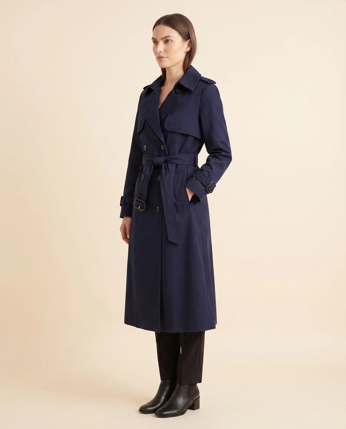 Angled view of navy belted trench coat showing long sleeves and side pocket