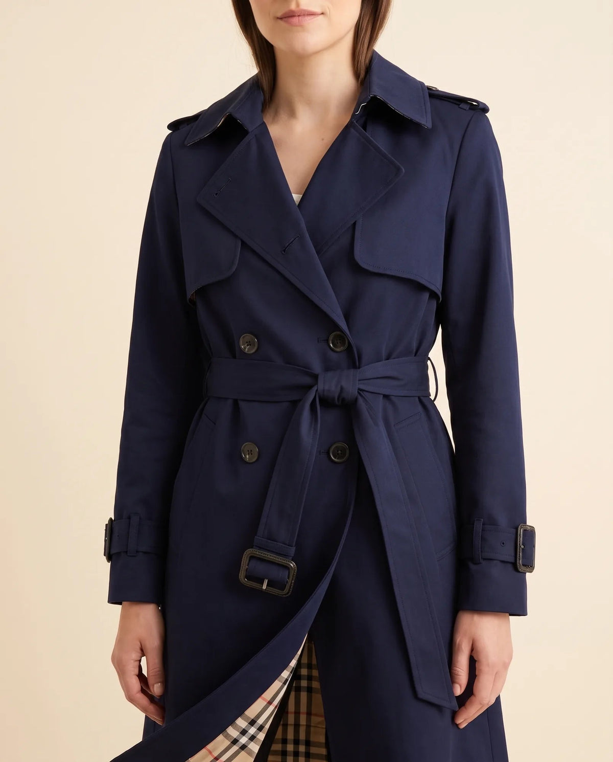 Close-up of navy trench coat showing notched lapels, double-breasted buttons and waist belt